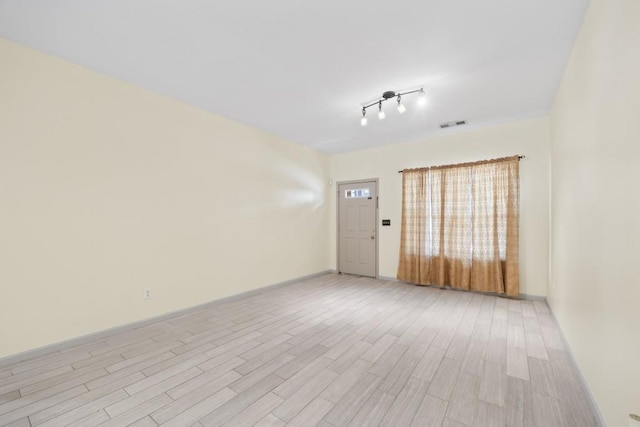 unfurnished room featuring rail lighting and light hardwood / wood-style flooring