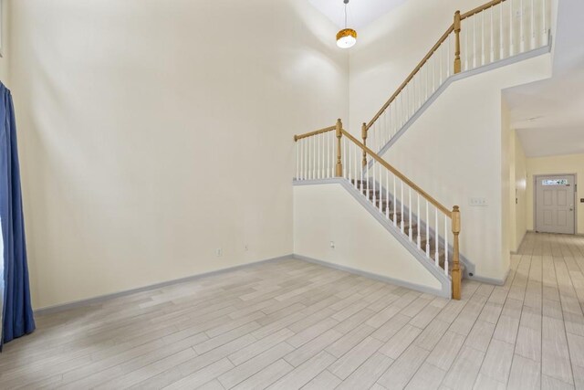 interior space with light hardwood / wood-style floors and a towering ceiling