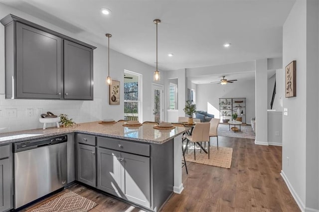 kitchen featuring tasteful backsplash, gray cabinets, dishwasher, kitchen peninsula, and light stone countertops