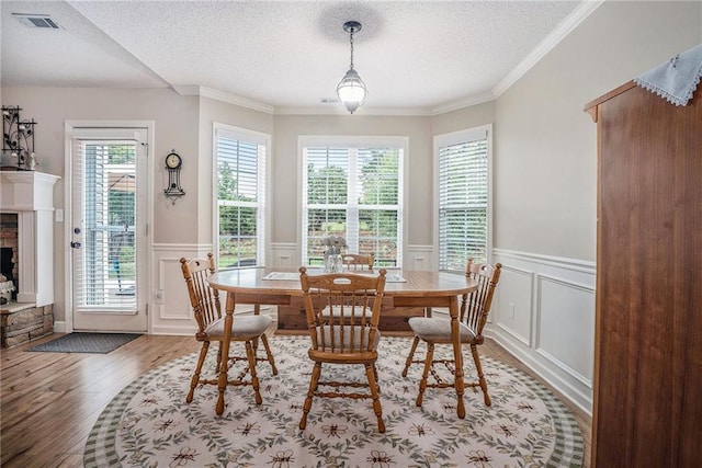 287 Jeremy Dr, Colbert, GA 30628 - dining area featuring wood finished floors, a textured ceiling, a decorative wall, wainscoting, and a fireplace with raised hearth