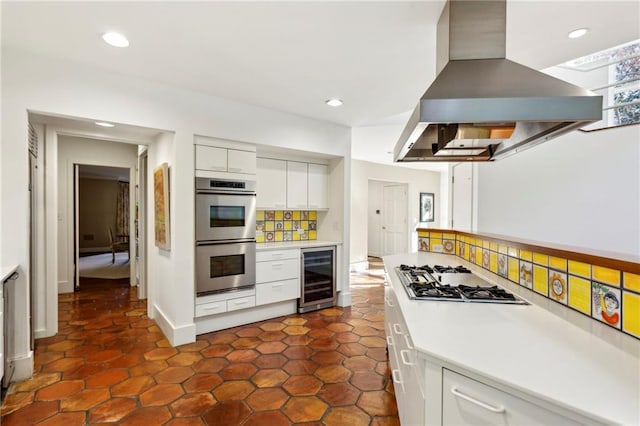 kitchen with white cabinets, wine cooler, tasteful backsplash, island exhaust hood, and stainless steel appliances