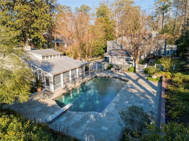 view of swimming pool with a diving board and a patio