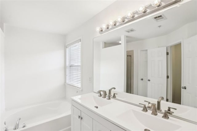 bathroom with a sink, double vanity, a bath, and visible vents