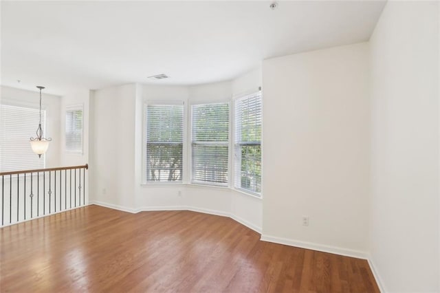 spare room featuring baseboards, wood finished floors, and visible vents