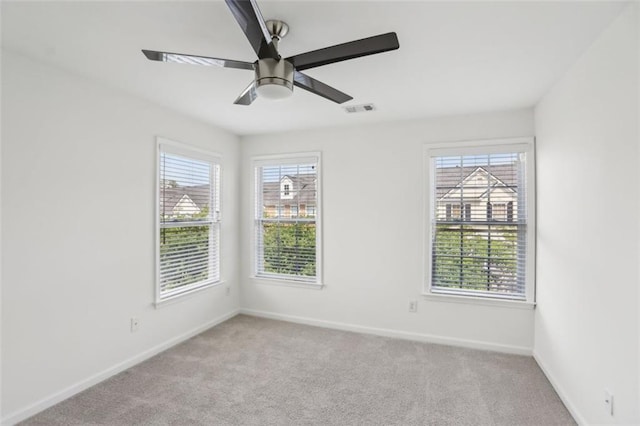 unfurnished room with visible vents, carpet flooring, baseboards, and plenty of natural light