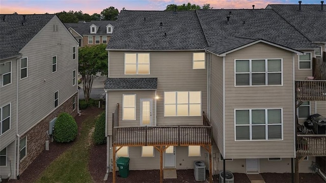 rear view of house with a shingled roof, central AC, and a wooden deck