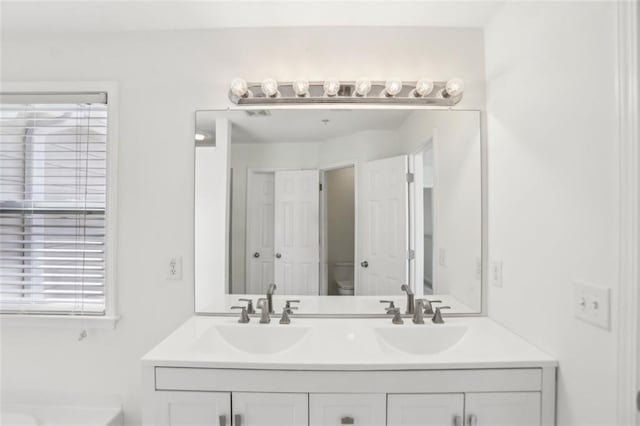 bathroom with double vanity, toilet, and a sink