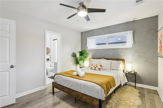 bedroom featuring visible vents, ensuite bathroom, a ceiling fan, wood finished floors, and baseboards