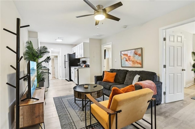 living area with ceiling fan and light wood finished floors