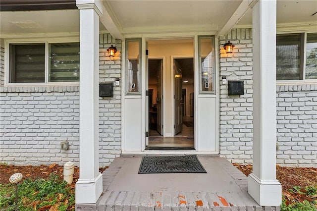 entrance to property featuring covered porch and brick siding