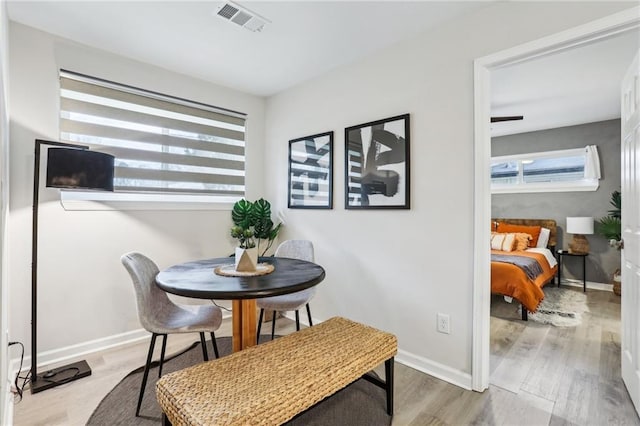 dining area with wood finished floors, visible vents, and baseboards