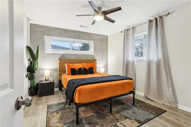 bedroom with visible vents, ceiling fan, baseboards, and wood finished floors