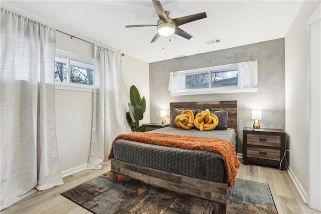 bedroom featuring light wood finished floors, baseboards, visible vents, and ceiling fan