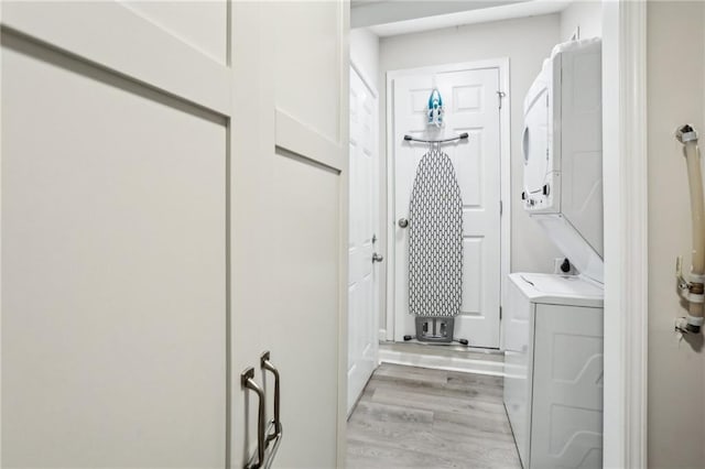 washroom featuring laundry area, light wood-style flooring, and stacked washer and clothes dryer