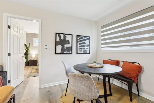 dining area with baseboards, breakfast area, and light wood-style floors