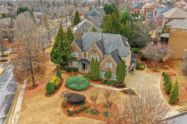 view of front of home with stone siding, roof with shingles, concrete driveway, and a residential view