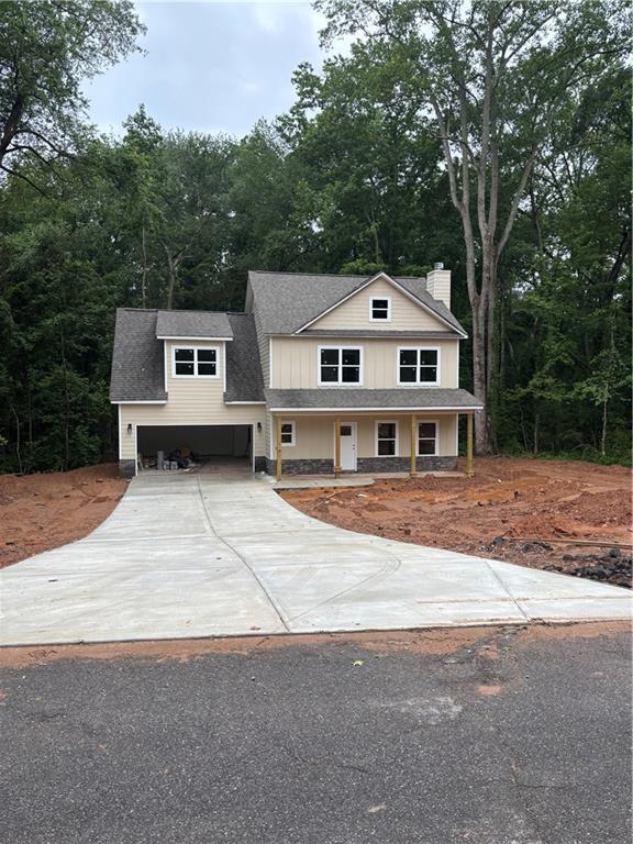 742 Joy St, Jackson, GA 30233 - view of front facade featuring board and batten siding, a chimney, covered porch, and roof with shingles