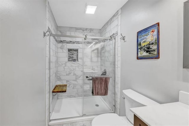 bathroom featuring vanity, toilet, and a shower with shower door