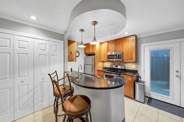 kitchen featuring appliances with stainless steel finishes, decorative light fixtures, a breakfast bar area, light tile patterned floors, and crown molding