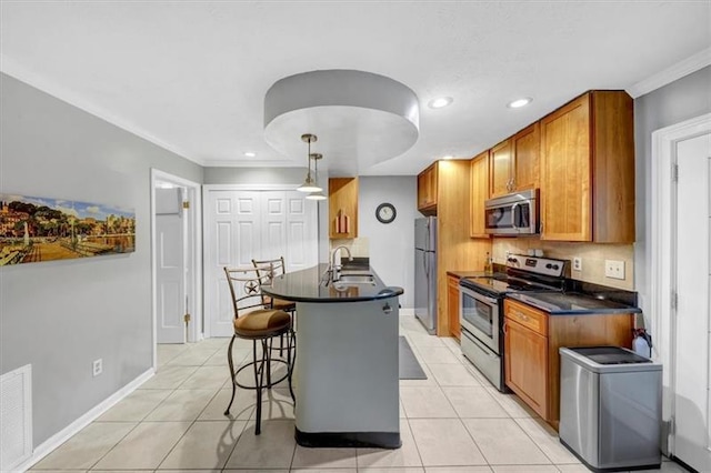 kitchen featuring light tile patterned flooring, sink, a breakfast bar area, hanging light fixtures, and appliances with stainless steel finishes