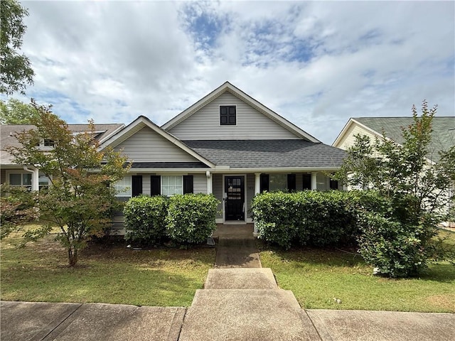 view of front facade with roof with shingles, a front lawn, and a porch
