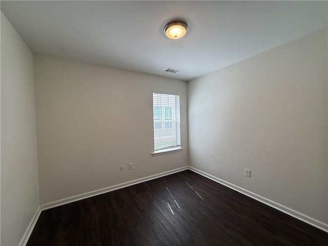 spare room with dark wood-type flooring and baseboards
