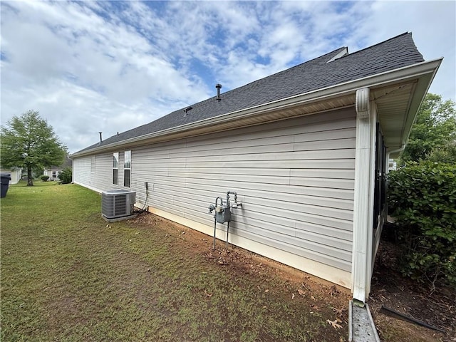 view of property exterior with central AC unit, a yard, and roof with shingles