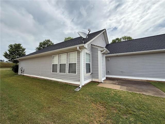 view of side of property featuring a patio and a lawn