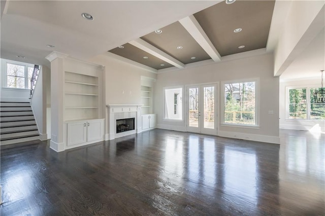 unfurnished living room with beamed ceiling, dark wood-type flooring, french doors, and built in shelves