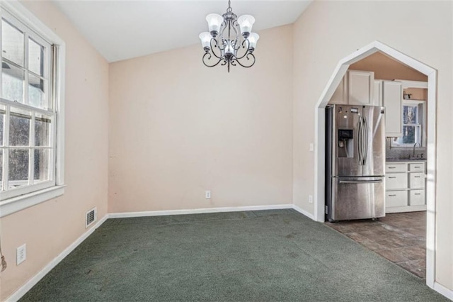 unfurnished dining area featuring visible vents, carpet floors, a notable chandelier, and a sink