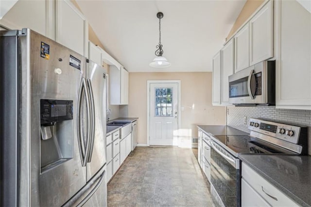kitchen with backsplash, dark countertops, a sink, hanging light fixtures, and appliances with stainless steel finishes