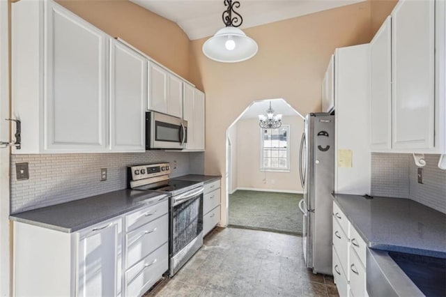 kitchen featuring white cabinets, dark countertops, tasteful backsplash, and stainless steel appliances