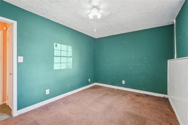 carpeted spare room featuring a ceiling fan, baseboards, and a textured ceiling