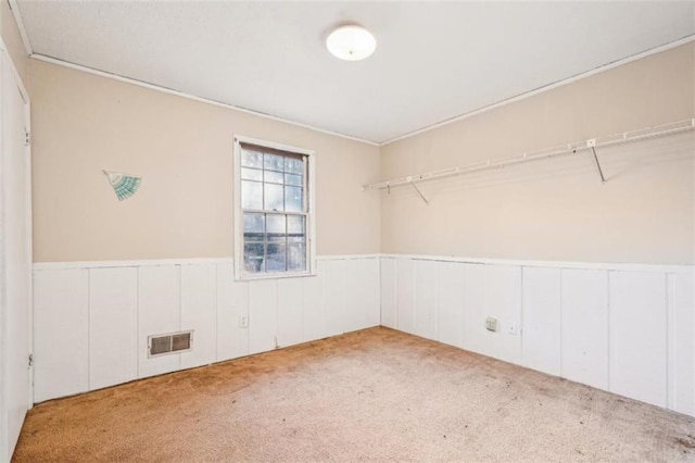 unfurnished room featuring wainscoting, visible vents, and carpet