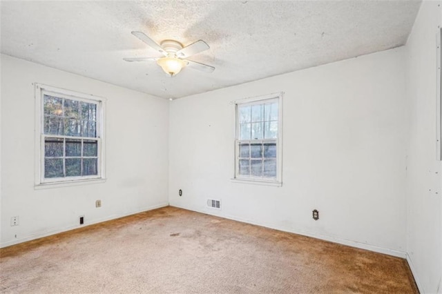 carpeted spare room with baseboards, a ceiling fan, visible vents, and a textured ceiling