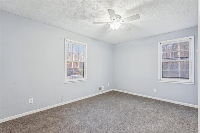 carpeted spare room with ceiling fan, baseboards, a textured ceiling, and visible vents