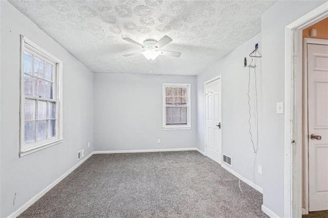 carpeted empty room with ceiling fan, baseboards, a textured ceiling, and visible vents