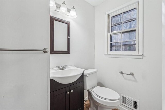 half bath featuring toilet, vanity, and visible vents