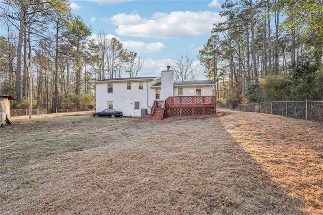 rear view of house featuring a fenced backyard, a chimney, and a deck