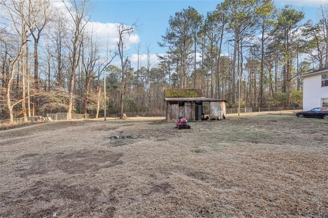 view of yard featuring an outdoor structure, a carport, and fence
