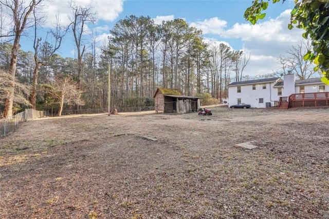 view of yard with fence, a wooden deck, and an outdoor structure