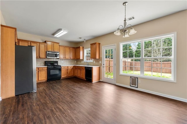 kitchen featuring dark wood-style floors, light countertops, visible vents, backsplash, and black appliances