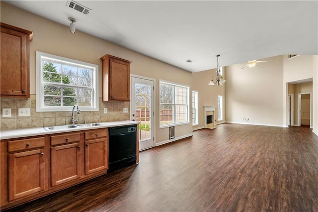 kitchen featuring a sink, visible vents, backsplash, dishwasher, and brown cabinetry