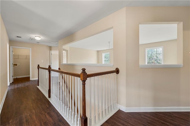 hall featuring attic access, plenty of natural light, baseboards, and wood finished floors