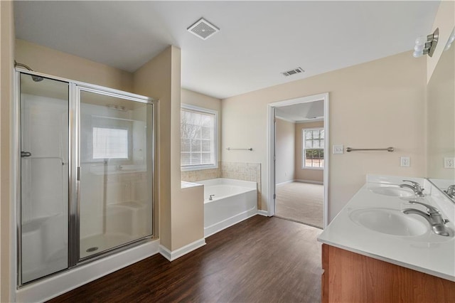 bathroom with a garden tub, wood finished floors, a stall shower, and a sink