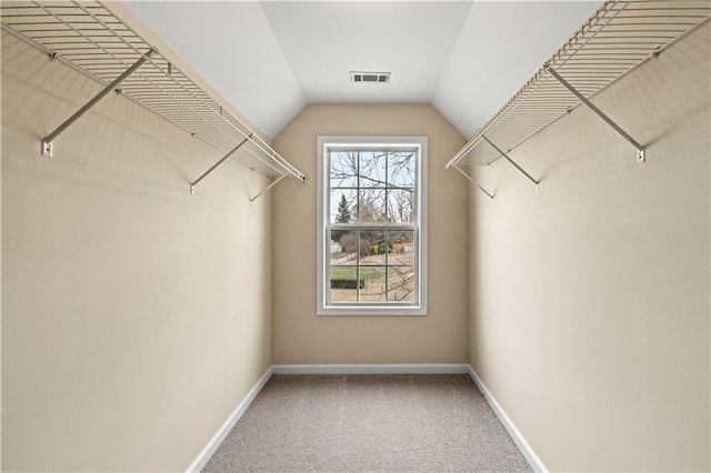 walk in closet with carpet, visible vents, and vaulted ceiling