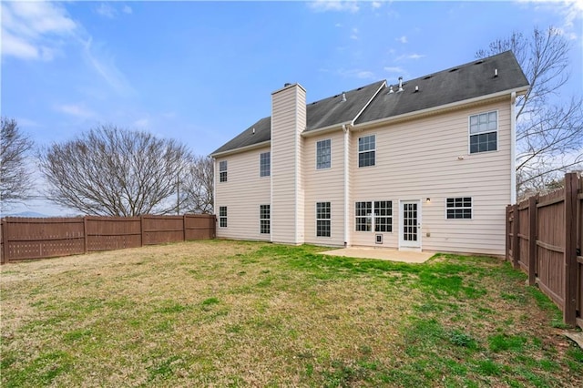 back of property featuring a patio, a lawn, a chimney, and a fenced backyard