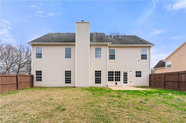 back of house featuring a patio area, a fenced backyard, a yard, and a chimney