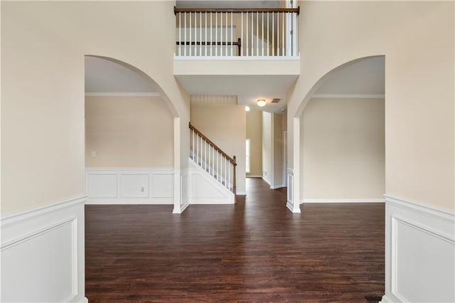 interior space with a wainscoted wall, stairway, a high ceiling, ornamental molding, and wood finished floors