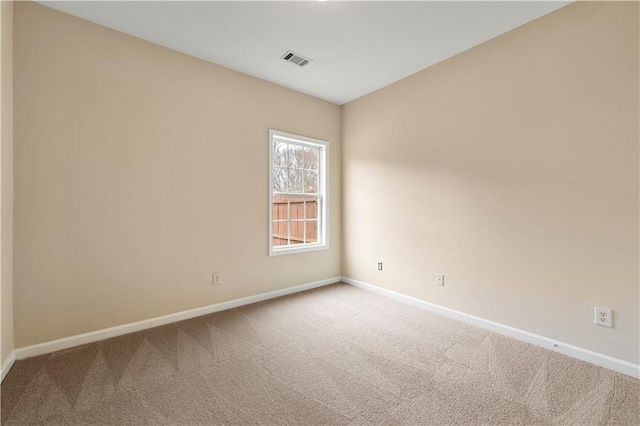 carpeted spare room featuring baseboards and visible vents